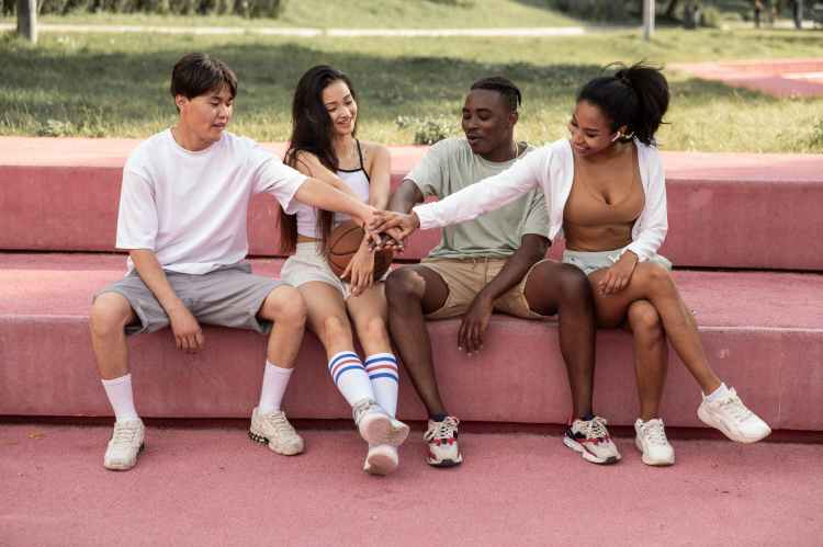 content diverse friends stacking hands on bench in park